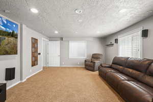 Living area with carpet, recessed lighting, and a textured ceiling