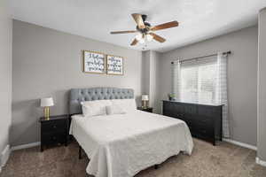 Carpeted bedroom with ceiling fan and a textured ceiling