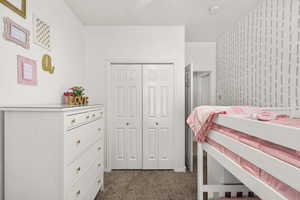 Bedroom with dark colored carpet and a closet