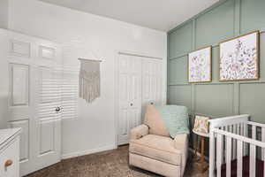 Bedroom with a decorative wall, a nursery area, dark colored carpet, and a closet
