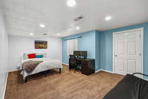 Bedroom featuring a textured ceiling, carpet flooring, recessed lighting, and a desk
