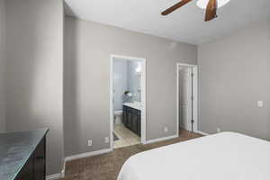Bedroom featuring light carpet, ensuite bathroom, and a ceiling fan