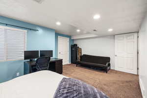 Bedroom featuring a textured ceiling, carpet floors, recessed lighting, and a desk