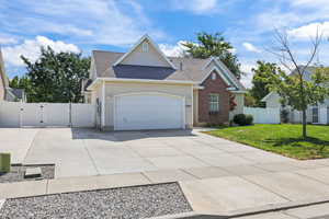 Traditional-style home featuring a gate, concrete driveway, a shingled roof, and an attached garage