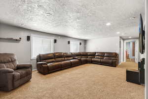 Living room with light colored carpet, a textured ceiling, and recessed lighting