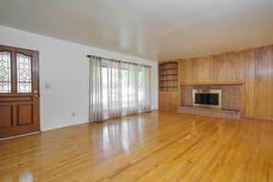 Unfurnished living room with light wood-style floors, a fireplace, and built in features