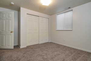 Unfurnished bedroom featuring a textured ceiling, carpet, and a closet