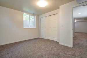 Unfurnished bedroom with a textured ceiling, carpet floors, and a closet