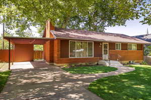 Ranch-style house featuring an attached carport, a chimney, and roof with shingles