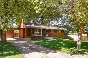 Single story home with an attached carport, a chimney, and concrete driveway