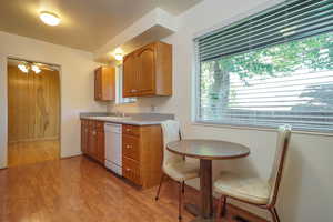 Kitchen featuring light wood-type flooring, healthy amount of natural light, light countertops, and white dishwasher