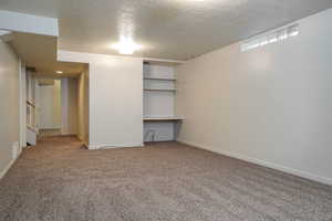 Unfurnished room featuring light colored carpet, a textured ceiling, and stairs