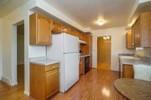 Kitchen featuring light wood-type flooring, freestanding refrigerator, and black range with electric cooktop