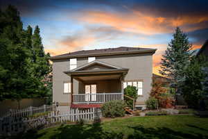 Rear view of property with stucco siding and a porch