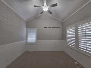 Den featuring new carpet, lofted ceiling with shipboard accent, a ceiling fan, and crown molding