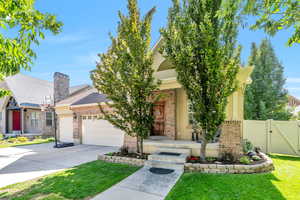 View of front of home featuring a gate, driveway, brick siding, and an attached garage