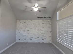 Master bedroom with vaulted ceiling, ceiling fan, and brick accent wall