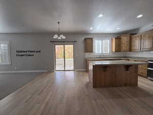 Kitchen featuring a textured ceiling, hanging light fixtures, a center island, a kitchen bar, and a chandelier