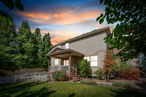 Back of property at dusk featuring stucco siding and a porch