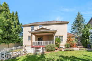 Rear view of house featuring stucco siding and covered porch