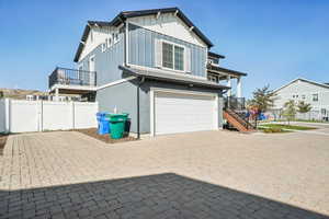 View of side of property with a garage, board and batten siding, driveway, stairs, and a gate