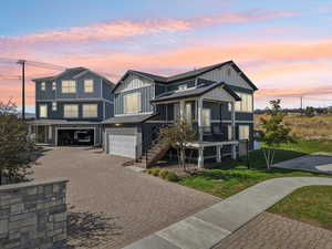 View of front facade with board and batten siding, decorative driveway, an attached garage, and stairs