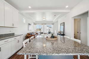 Kitchen featuring a breakfast bar, a raised ceiling, and dark stone counters