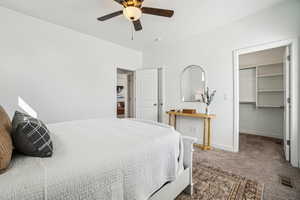 Carpeted bedroom with a spacious closet and ceiling fan