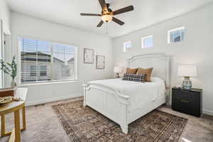 Carpeted bedroom featuring ceiling fan and baseboards