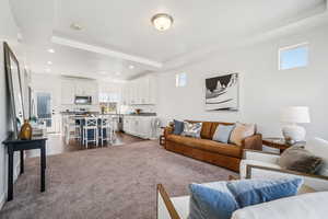 Living area featuring dark colored carpet, a tray ceiling, and recessed lighting