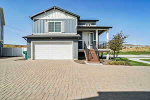 View of front facade featuring a garage, decorative driveway, board and batten siding, stairs, and a porch