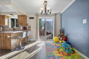 Recreation room with wood finished floors, crown molding, and a chandelier