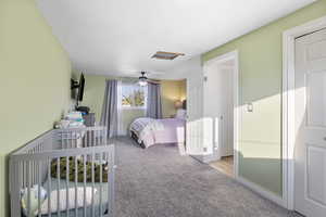 Bedroom with light carpet, attic access, and a ceiling fan