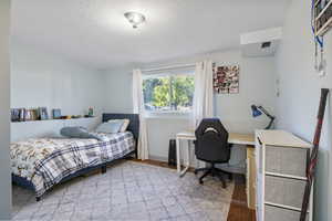 Bedroom with light wood-style flooring, a desk, and a textured ceiling