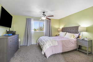 Bedroom with light colored carpet and a ceiling fan