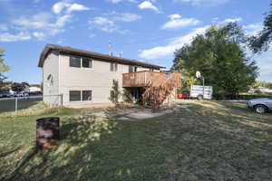 Rear view of house with a wooden deck, stairs, and a patio