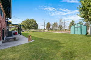 Fenced backyard featuring a patio area and a storage shed