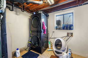 Washroom with tile patterned flooring and stacked washer and clothes dryer