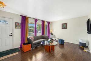 Living room with dark wood-style floors and baseboards