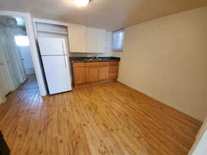 Kitchen with freestanding refrigerator, light wood-style flooring, brown cabinets, and white cabinets