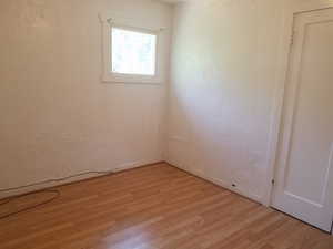 Empty room with a textured wall and light wood-type flooring