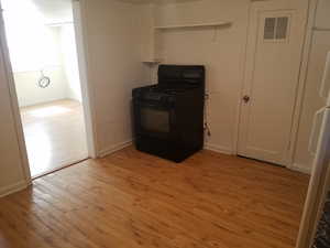 Kitchen featuring light wood-type flooring, black range with gas cooktop, and fridge