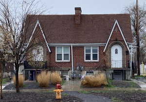View of front of house featuring a chimney, brick siding, and a shingled roof