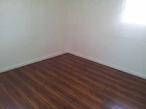 Spare room with dark wood-style flooring and baseboards