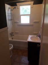 Full bathroom featuring bathing tub / shower combination, vanity, and dark tile patterned floors