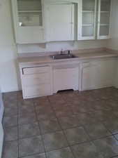 Kitchen featuring white cabinets, light countertops, and dark tile patterned floors