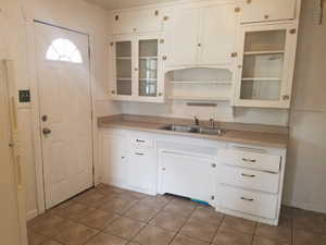 Kitchen with white cabinetry, freestanding refrigerator, glass insert cabinets, and light countertops