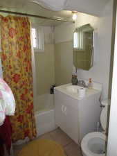 Full bathroom with shower / bathtub combination with curtain, light tile patterned floors, and vanity