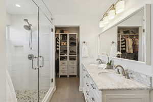 Full bathroom featuring a spacious closet, a stall shower, and double vanity