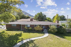 Single story home with brick siding, a chimney, a mountain view, and a shingled roof